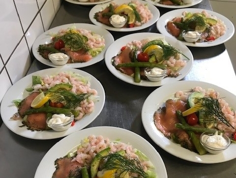 Anretninger med laks, rejer og grønt klar til servering fra køkkenet