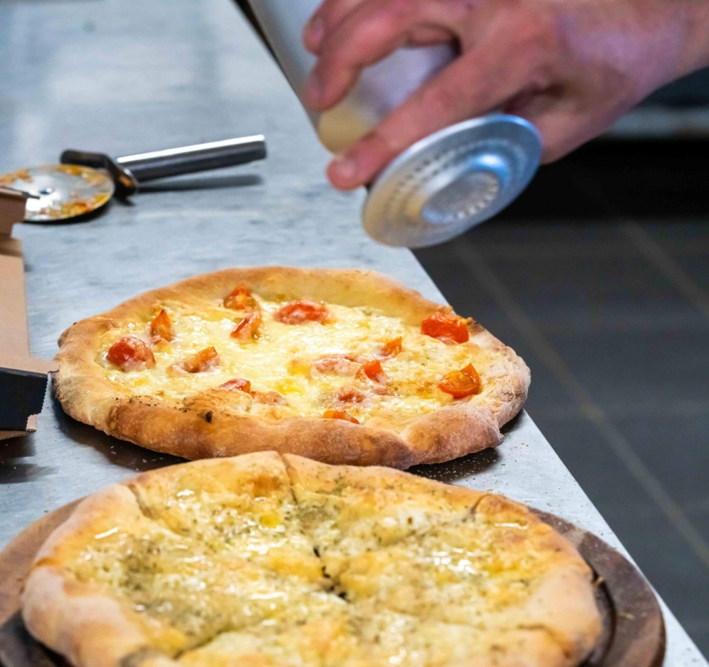 Kok tilbereder frisk pizza med ost og tomat hos Italia i Grenaa